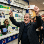 Man celebrating with winning lottery ticket inside lottery office